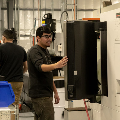 A young machinist uses a CNC machine.